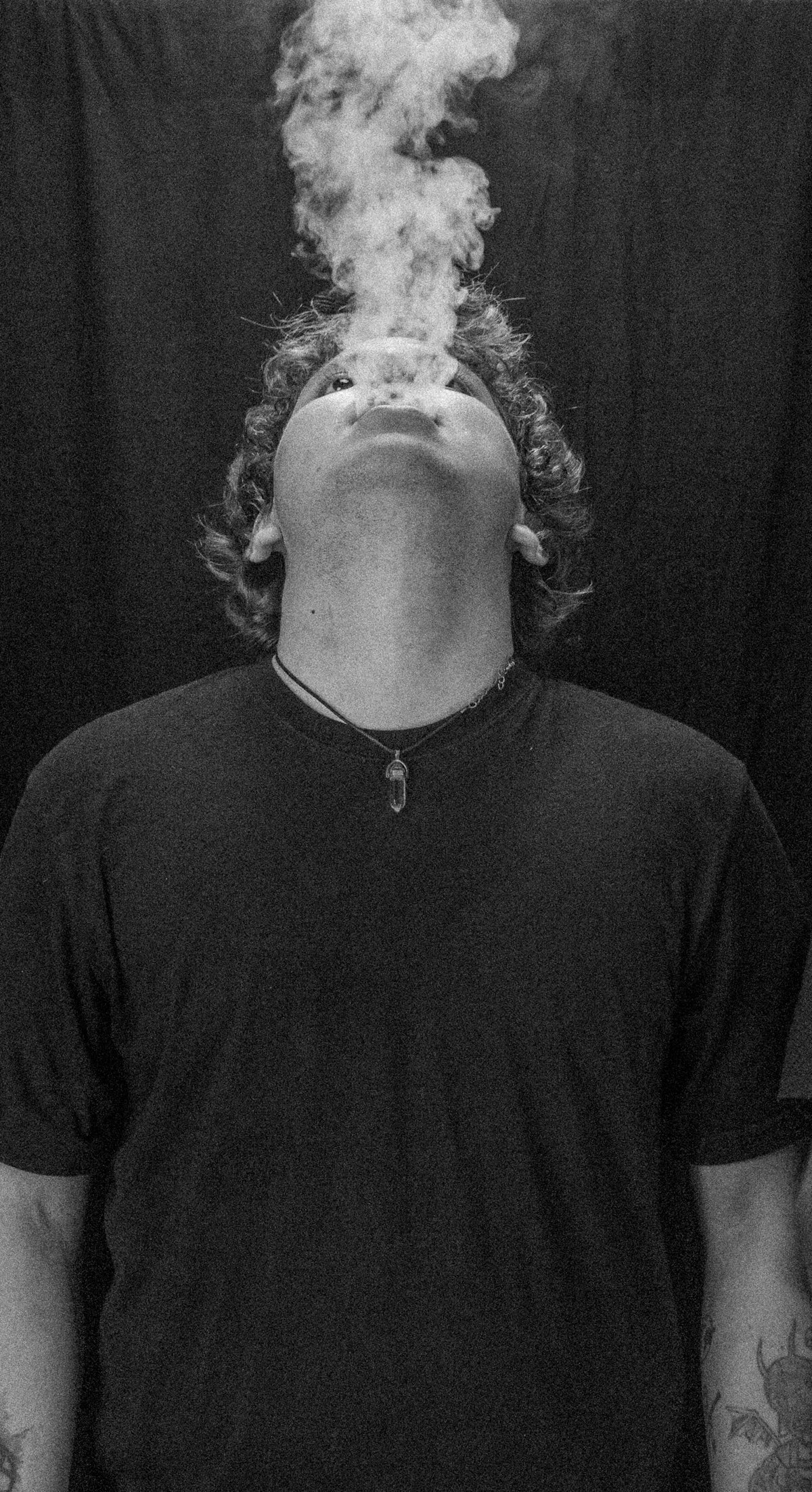 Man exhaling smoke against a dark background