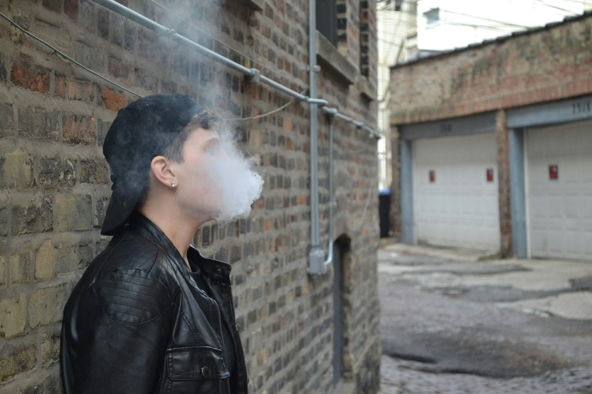 Person exhaling smoke in an urban alleyway